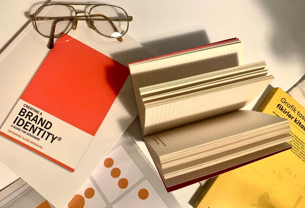 Brand identity book next to open notebook and glasses.