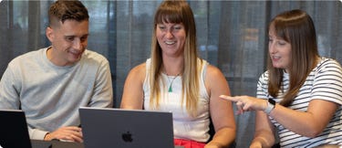 Three Blackpepper team members working together around a laptop